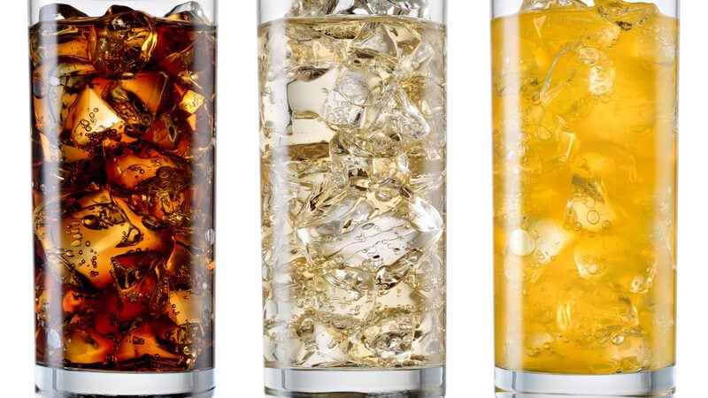 Drei volle Gläser mit Eiswürfeln (Cola, weiße und gelbe Limonade)