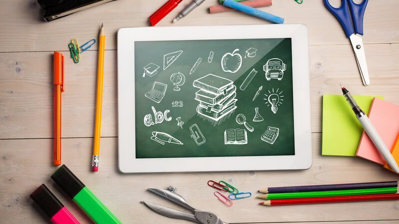 E-Learning: Tablet auf Tisch, im Gegenzug Stifte, Marker, Zettel und Schere