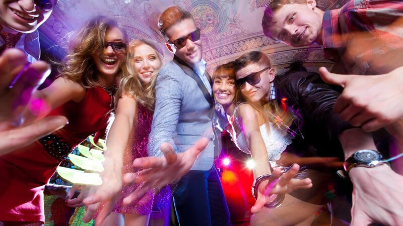 Sieben Jugendliche in Party-Outfit auf der Tanzfläche