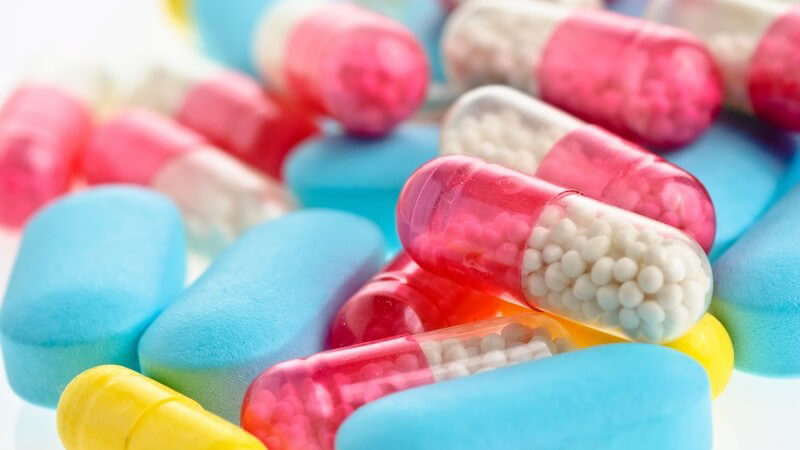Bunte Tabletten und Kapseln auf weißem Hintergrund