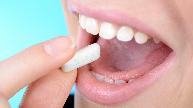 Frau steckt sich ein Zahnpflege-Kaugummi in den Mund