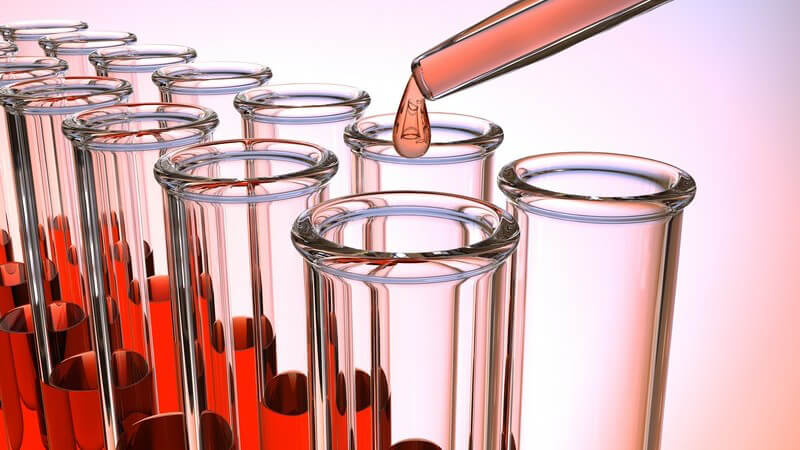 Reagenzgläser werden mit einer Glaspipette mit einer roten Flüssigkeit befüllt