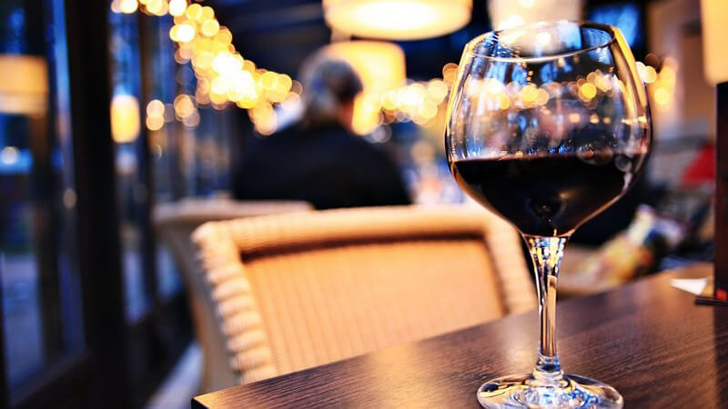 Glas Rotwein auf einem Tisch im Restaurant, der Stuhl ist leer