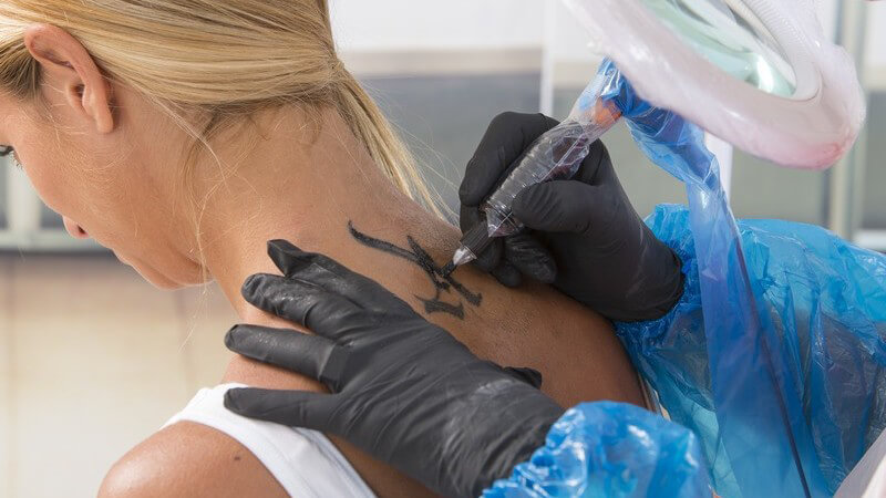 Blonde Frau bekommt ein Tattoo auf den Nacken tätowiert