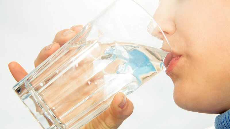 Frau nimmt einen Schluck Wasser aus einem großen Trinkglas