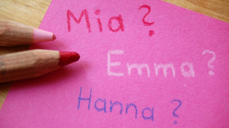Pinker Zettel mit Mädchennamen neben Buntstiften