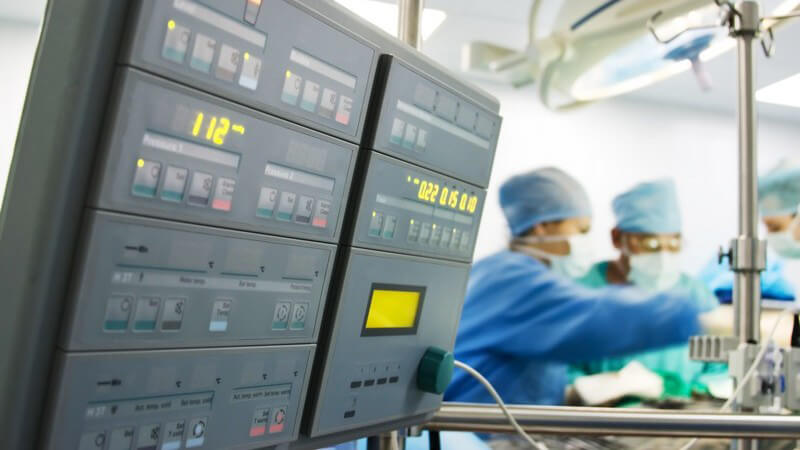 Kreislauf Kontrollgerät in Operationssaal, im Hintergrund Chirurgen bei OP