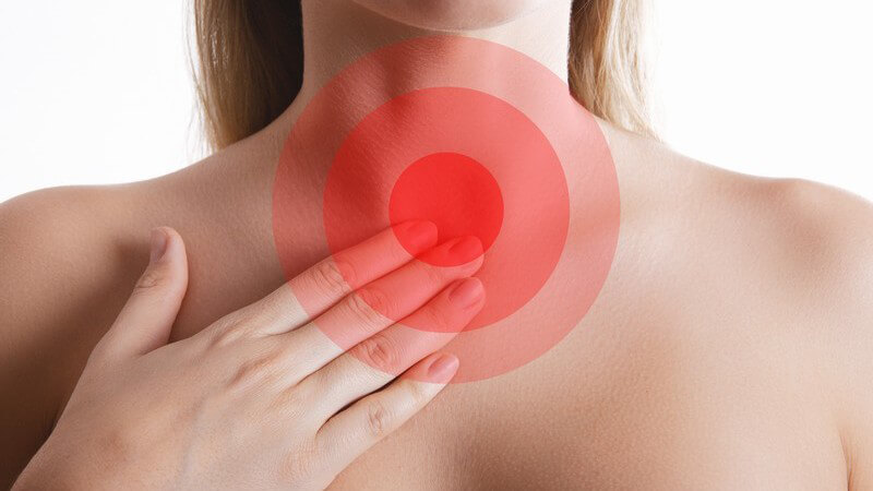 Frau fasst sich an den Halsbereich, rote Kreismarkierungen in Höhe der Luft-/Speiseröhre