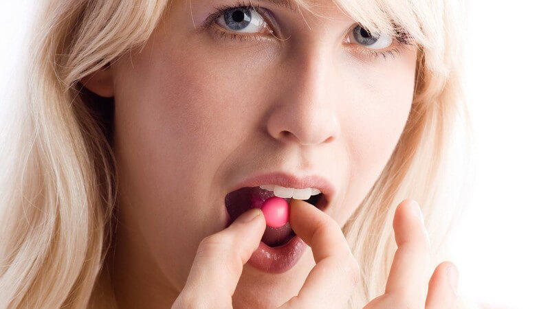 Blonde Frau nimmt Pille in Mund