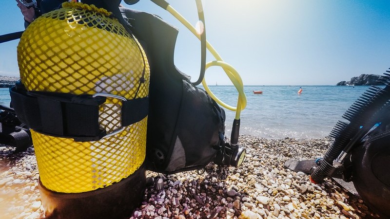 Gelbe Tauchflasche und andere Taucherausrüstung auf einem steinigen Strand