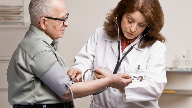 Ärztin misst Blutdruck bei älterem Mann