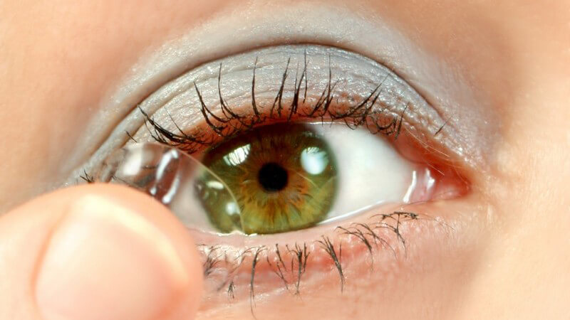 Kontaktlinse auf Fingerspitze wird vor Auge gehalten