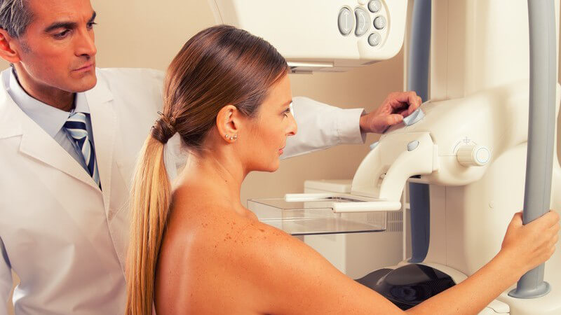 Arzt mit Patientin beim Einstellen eines Mammografie-Gerätes