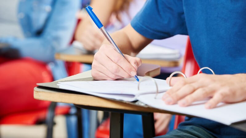 Schüler in blauem Shirt beim Schreiben im Schulunterricht