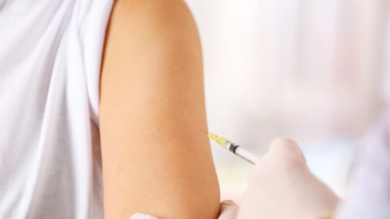 Arzt sticht eine Spritze in den Oberarm einer Frau, um sie zu impfen