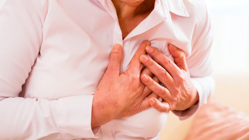 Herzinfarkt: Oberkörper einer Frau mit Brustschmerzen, sie fasst sich aufs Herz