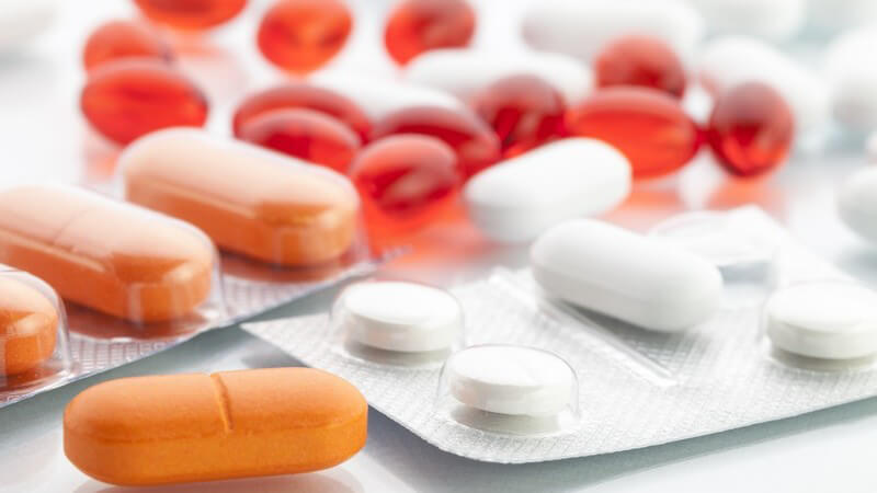 Rote, orangefarbene und weiße Tabletten neben oder in ihren Blistern