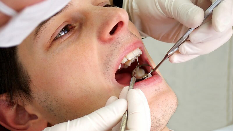 Mann, der von Zahnarzt im Mund untersucht wird