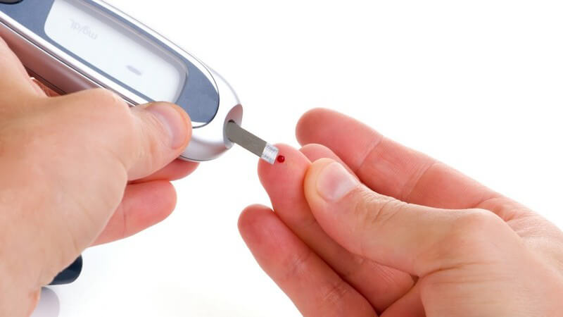 Hände eines Diabetikers, Bluttest in Fingerkuppe