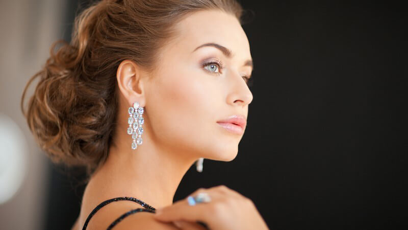 Glamuröse hübsche Frau mit hochgesteckten braunen Haaren und langen Diamant-Ohrringen