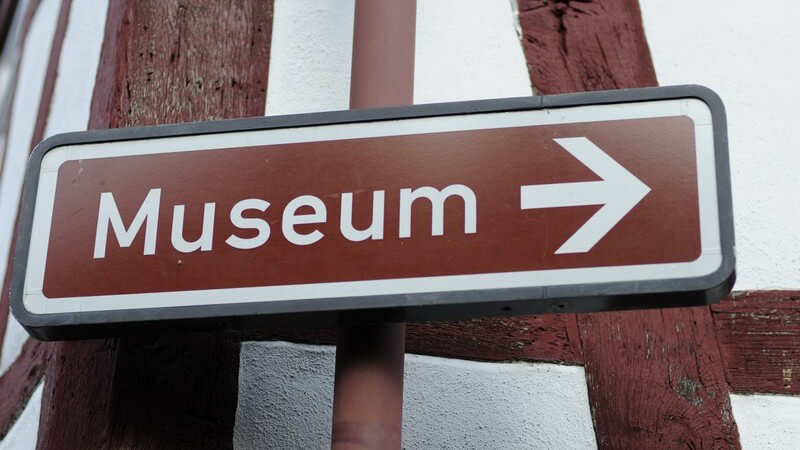 Braunes Schild auf dem in weißer Schrift Museum steht mit Pfeil nach rechts