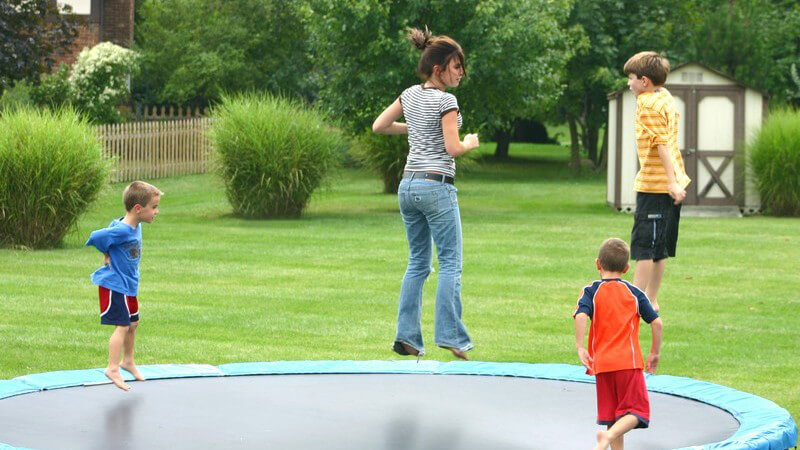 Kinder springen in großem Garten auf einem Trampolin
