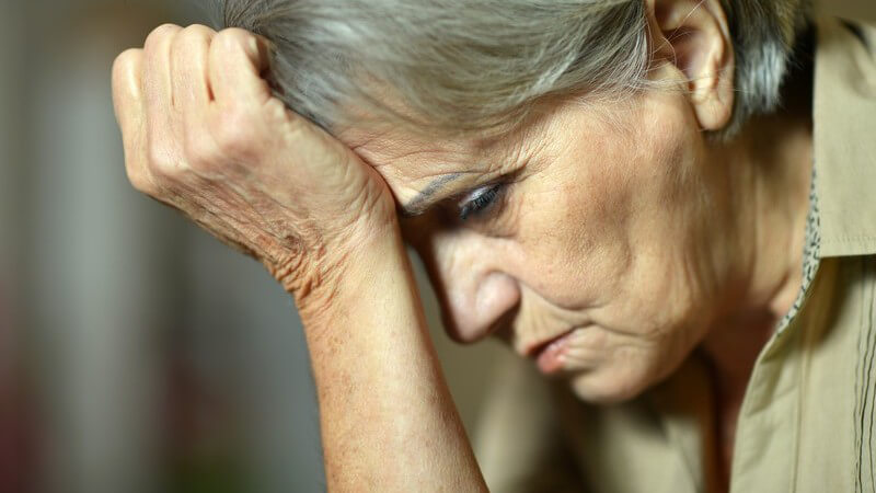 Traurige Seniorin, den Kopf ans Handgelenk gestützt