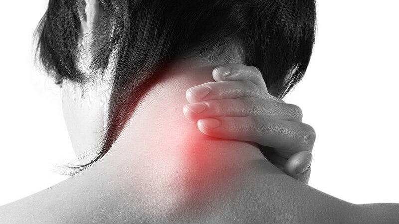 Schwarz-weiß Bild Rückenansicht Frau mit Nackenschmerzen hält rot beleuchteten Nacken