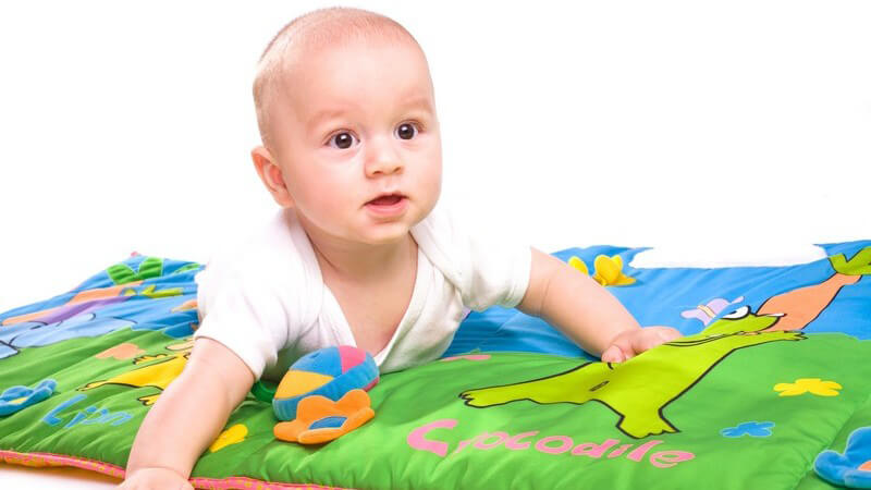 Baby spielt auf Krabbeldecke, weißer Hintergrund