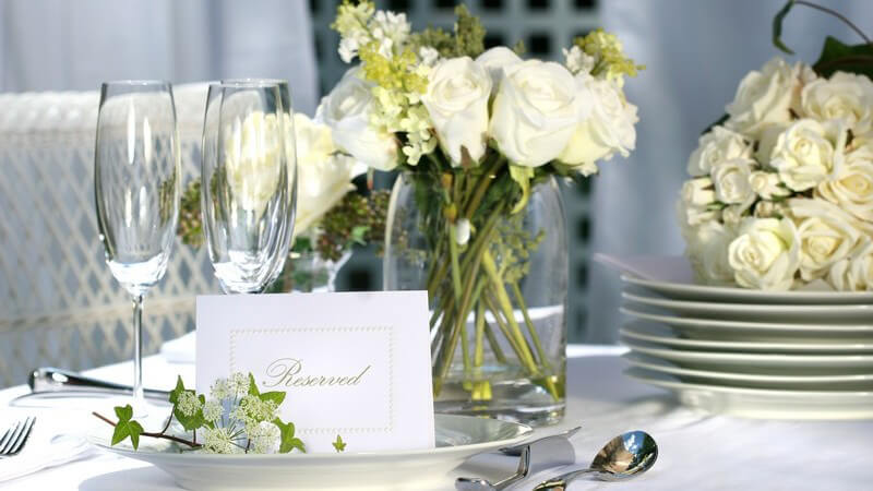 Gedeckter, reservierter Tisch mit weißen Rosen zur Hochzeit