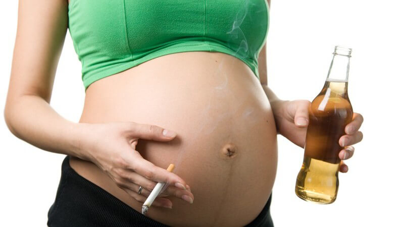 Schwangere Frau mit Zigarette und Alkohol in den Händen