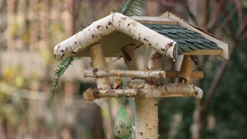 Vogelhaus aus Holz mit Tannenzweig und Körnerball