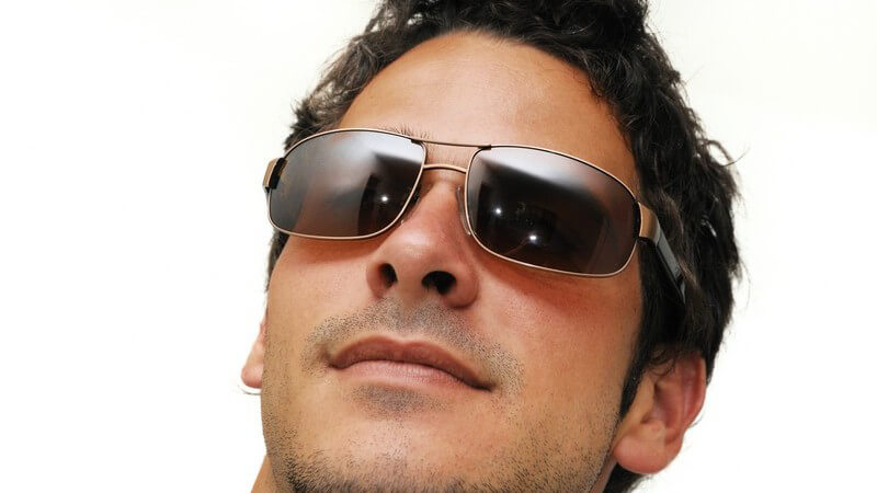 Gesicht eines jungen Mannes mit modischer Sonnenbrille auf weißem Hintergrund