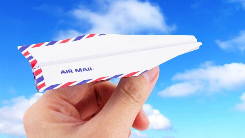 Hand hält Papier Flugzeug mit Aufschrift Air Mail unter blauem Himmel