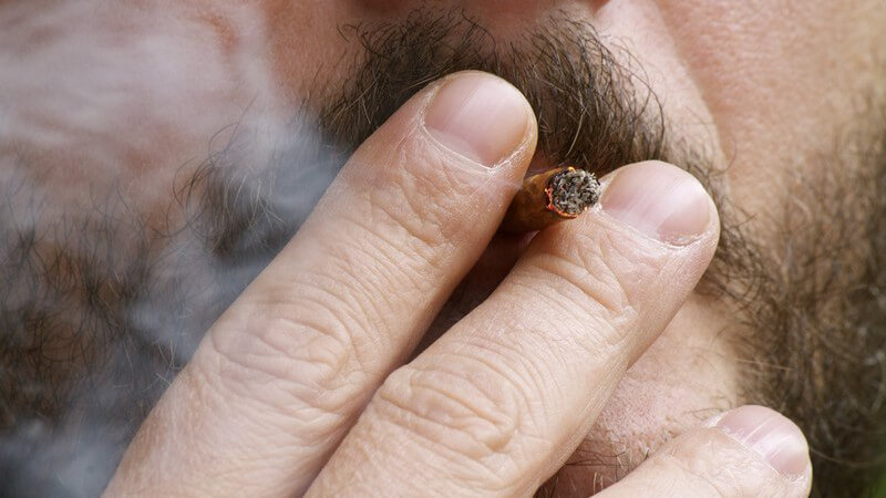 Mann mit Bart zieht an einer braunen Zigarette