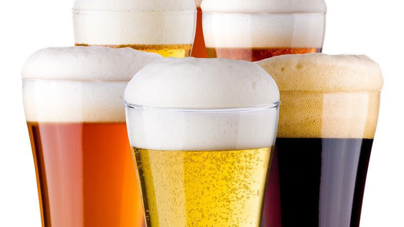 Sechs Gläser mit verschiedenen Biersorten auf weißem Hintergrund