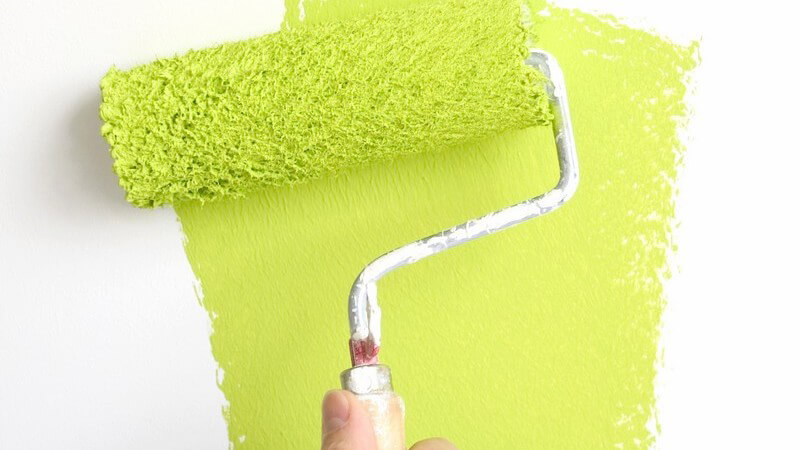 Nahaufnahme limettengrüne Farbe wird mit Farbrolle auf weiße Wand gestrichen
