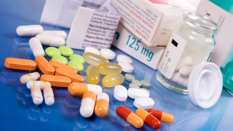Verschiedene Tabletten und Medikamentenpackungen auf blauem Tisch