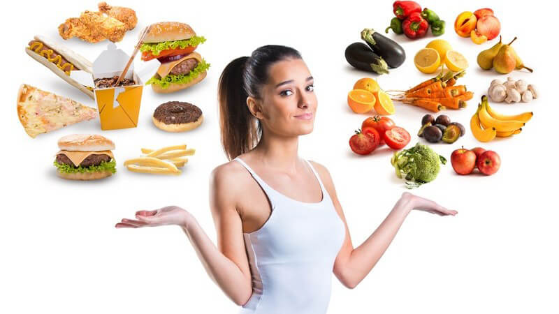 Ungesunde (Fast Food) und gesunde Nahrungsmittel (Obst und Gemüse) schweben über den Händen einer sportlichen Frau