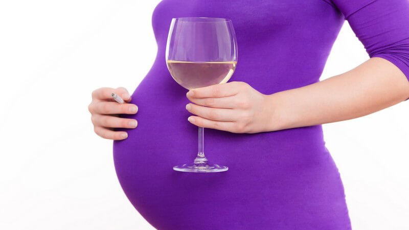 Schwangere Frau hält Glas mit Wein in der Hand
