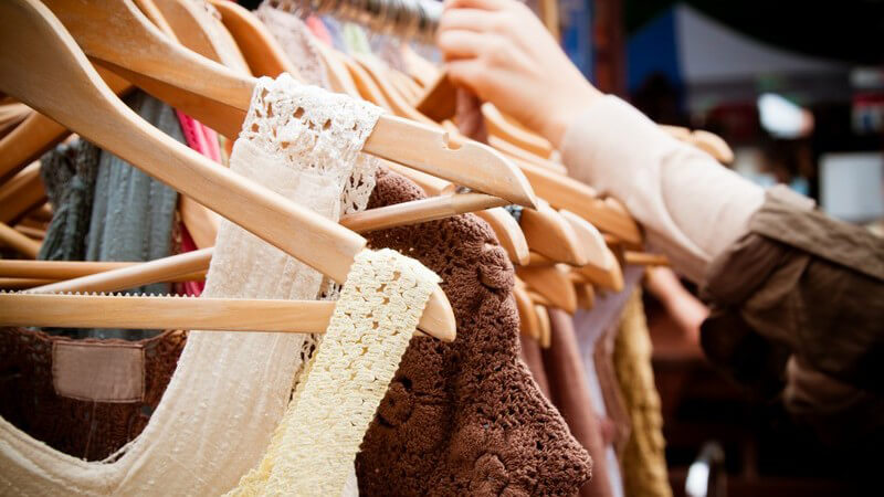 Kleiderstange in Damenboutique, Frauenhände an Kleidern, Frau beim Shoppen