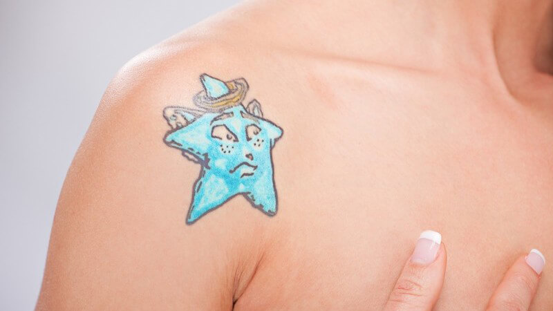 Tattoo, blauer Stern auf der Schulter einer Frau