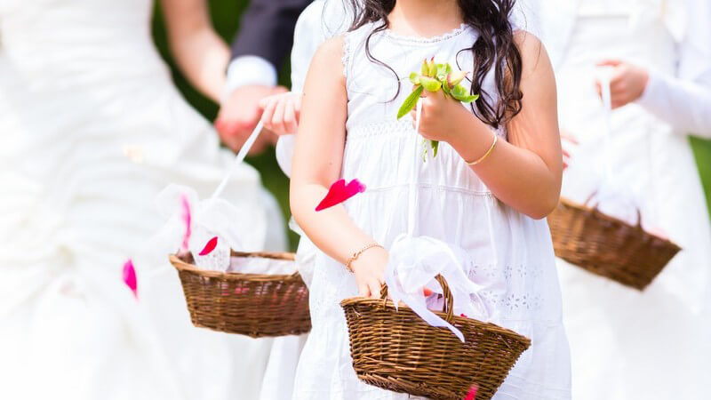 Brautjungfern mit Weidenkörbchen streuen Blütenblätter auf Hochzeit