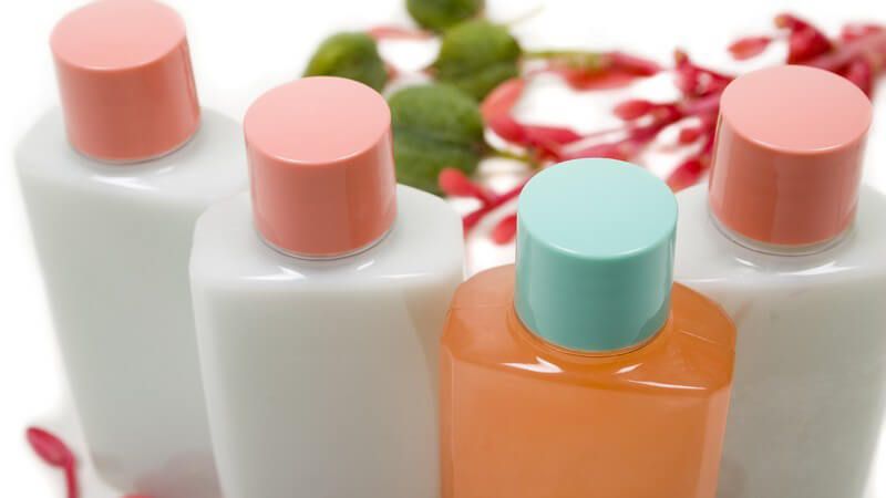 Vier Kosmetikflaschen mit Shampoo, Lotions oder Duschgel auf weißem Hintergrund