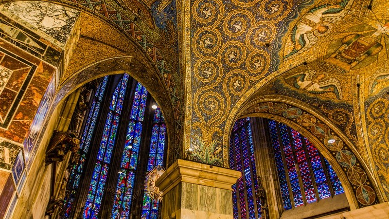 Blick an die hohen Decken im Aachener Dom, voller goldener Verzierungen und Malereien, mit verzierten blauen Fenstern
