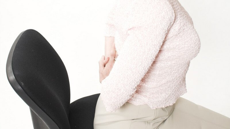 Seitenansicht Frau auf Bürostuhl macht Hohlkreuz, Rückenschmerzen