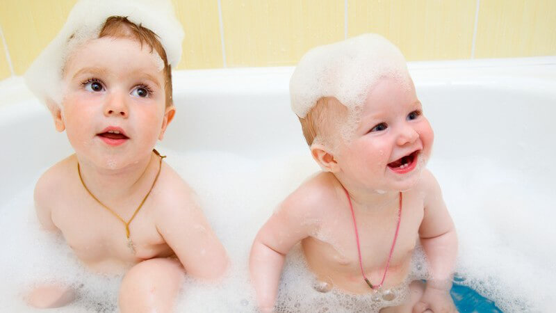 Kleinkind und Baby in Badewanne mit viel Schaum