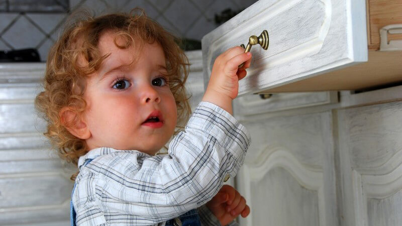 Kleinkind macht Schublade in Küche auf Kindersicherheit Gefahr Risiko