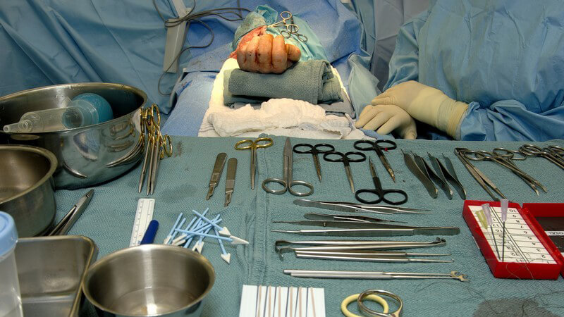 Hand Operation im OP Saal, davor Tisch mit sämtlichen Operationswerkzeugen