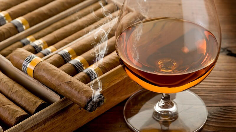 Cognac im Glas, daneben Zigarren